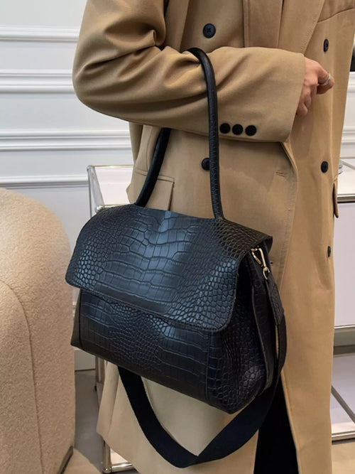Black crocodile-embossed flap shoulder bag with curved top and adjustable strap